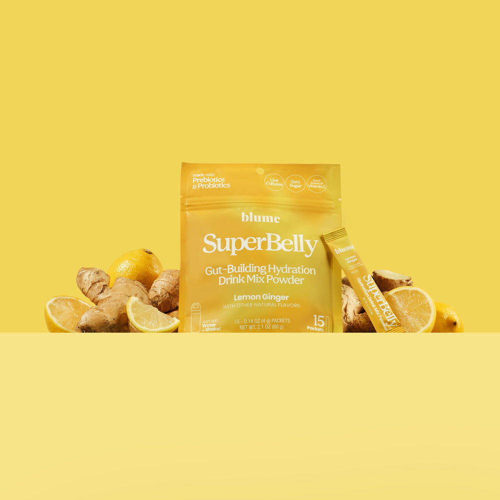 Lemon Ginger Superbelly Drink Mix Package with fresh ginger and lemon slices on a yellow backdrop